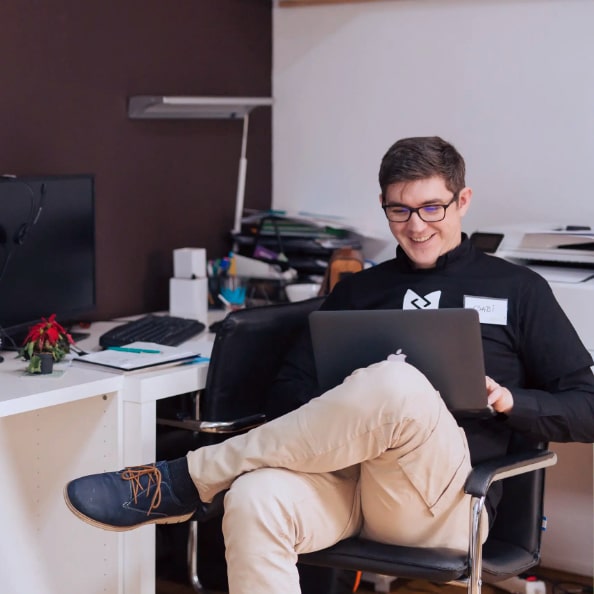 happy website maintenance client-min man sitting in a chair looking at his laptop smiling about his website